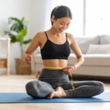 日本人女性が自宅でリラックスしながらウエストを測り、楽しくダイエットに取り組んでいる様子